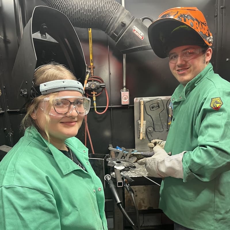 Photo of 2 teens in a manufacturing environment, learning about the trade