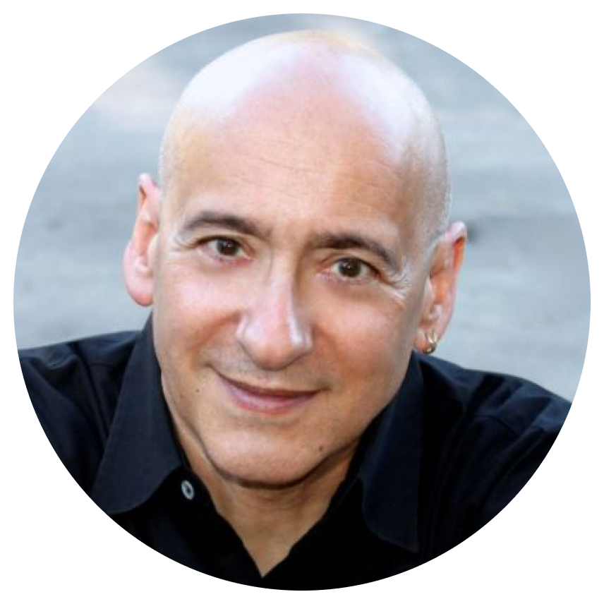 Close up headshot of Allan Rich, award nominated songwriter, smiling warmly at the camera with his arms folded and wearing a black button down shirt.