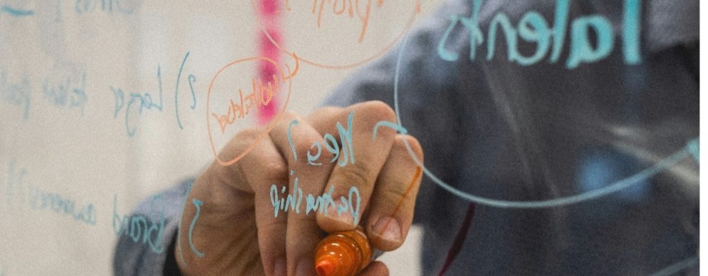 A closeup of someone writing on a glass whiteboard